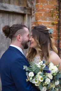 A bride and groom share a kiss in front of a brick wall during their wedding photography session in Bath.