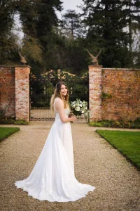 A bride in a white wedding dress standing in front of a gate, captured in beautiful wedding photography.