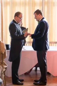 _MIN6771 Orchardleigh Wedding Photography captures the timeless moment of two men exchanging rings at a wedding ceremony.