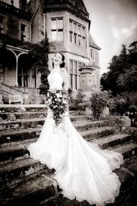 A bride is posing on the steps of Farleigh House.