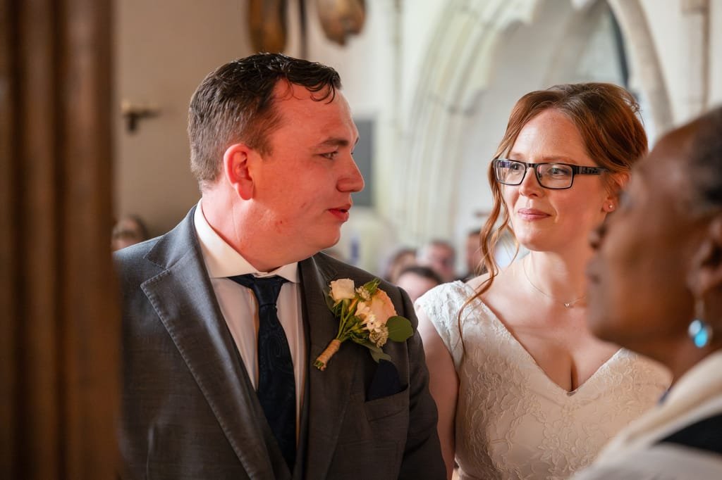 A bride and groom engaging in conversation with a wedding photographer at their ceremony inside Orchardleigh Church.