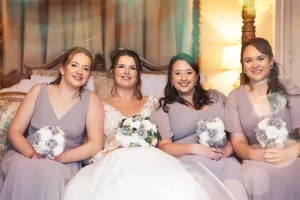 Four bridesmaids are posing for a picture on a bed during a wedding photoshoot with Orchardleigh's wedding photographer.