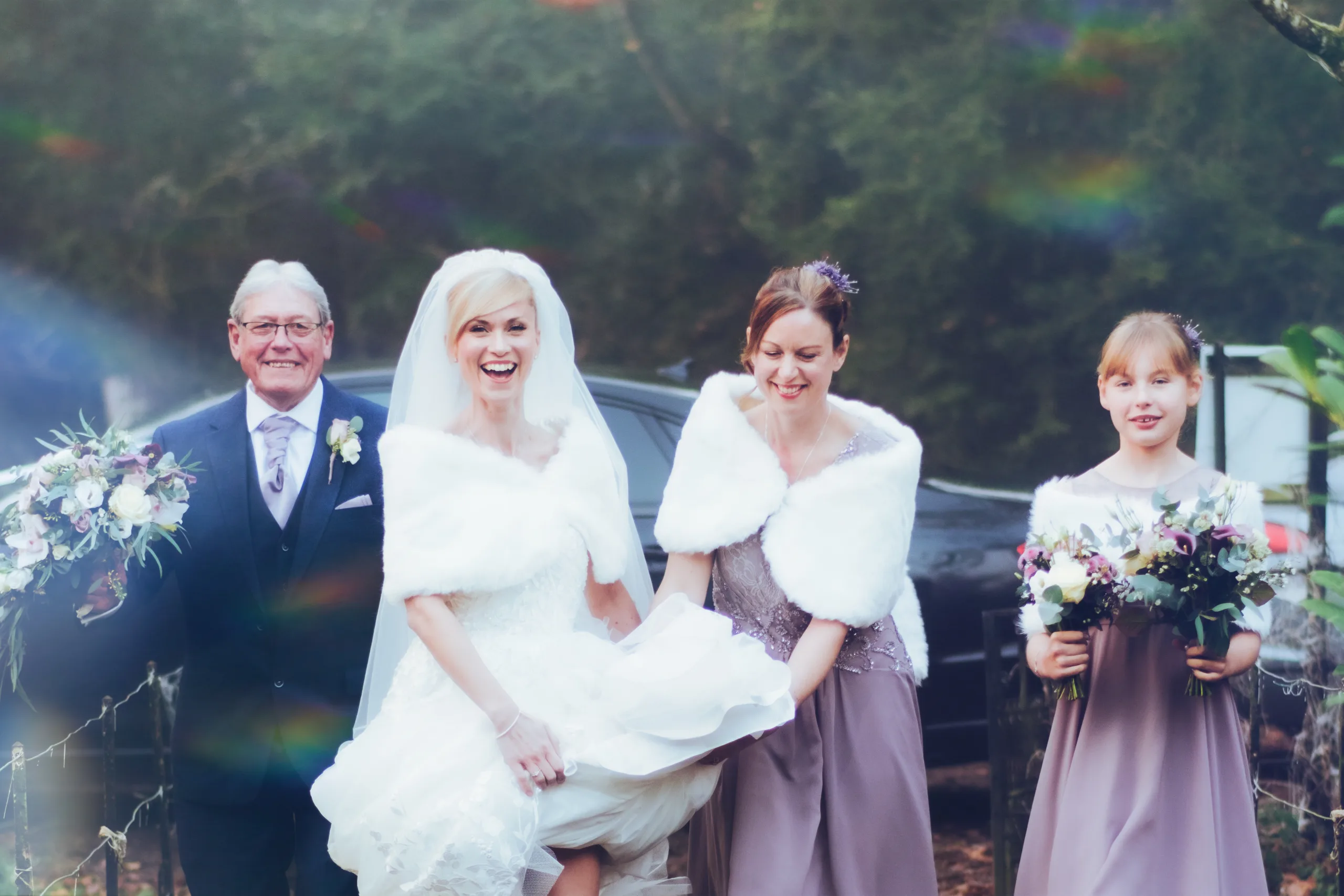 A bride and her bridesmaids are walking through the enchanting woods captured by Orchardleigh Wedding Photographer.