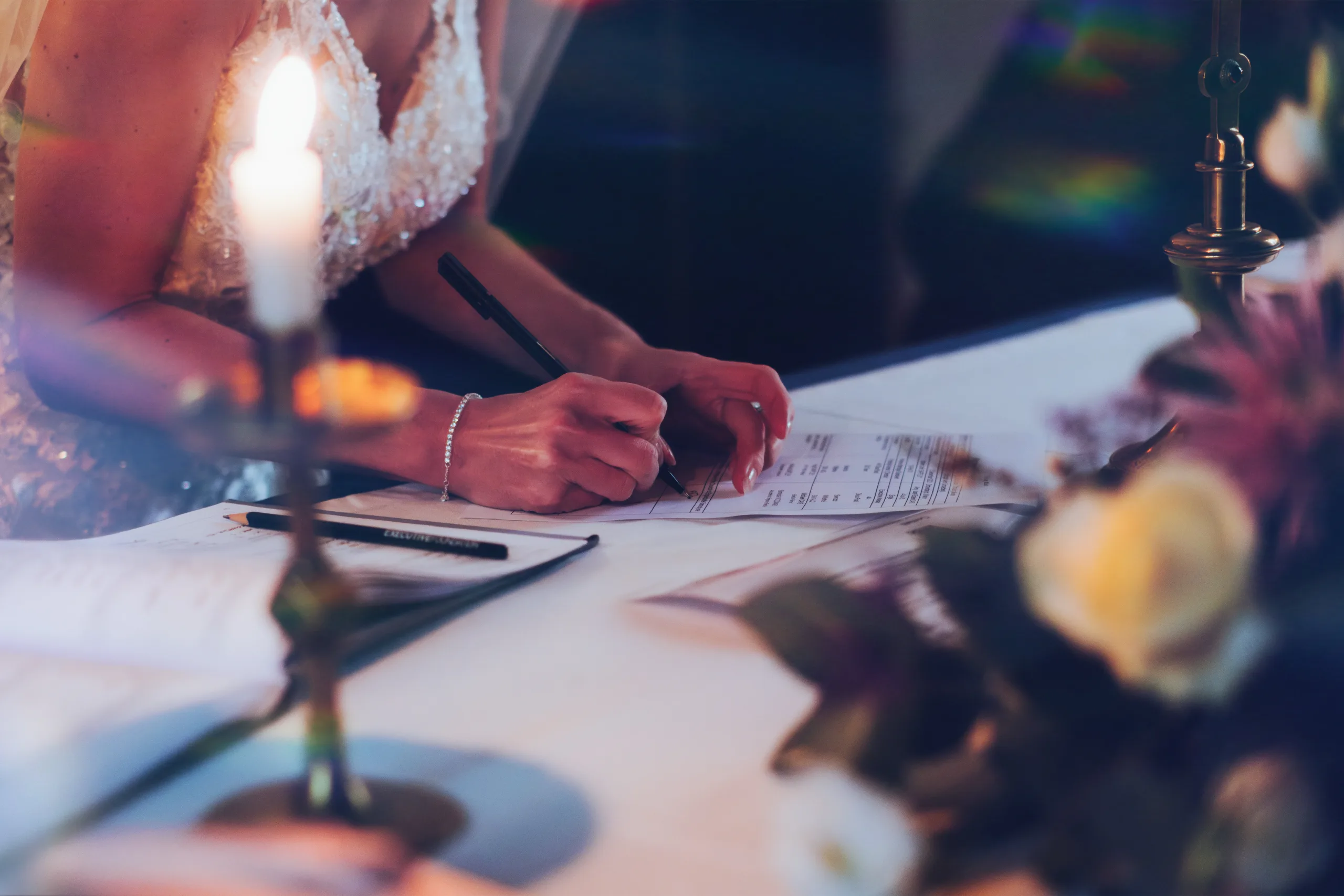 A bride signing her wedding vows at a table with candles captured by Orchardleigh Wedding Photographer.