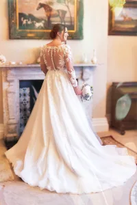 A bride in a wedding dress standing in front of a fireplace, captured by the talented Wedding Photographer at Orchardleigh.