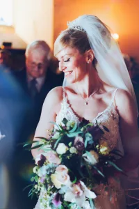 A bride at Orchardleigh House is holding a bouquet of flowers while posing for photos.