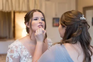 A bride is getting her makeup done by a Wedding Photographer at Orchardleigh.