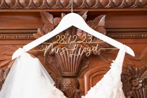 At Orchardleigh, a stunning wedding dress hangs gracefully on a wooden hanger awaiting the skilled eye of the wedding photographer.