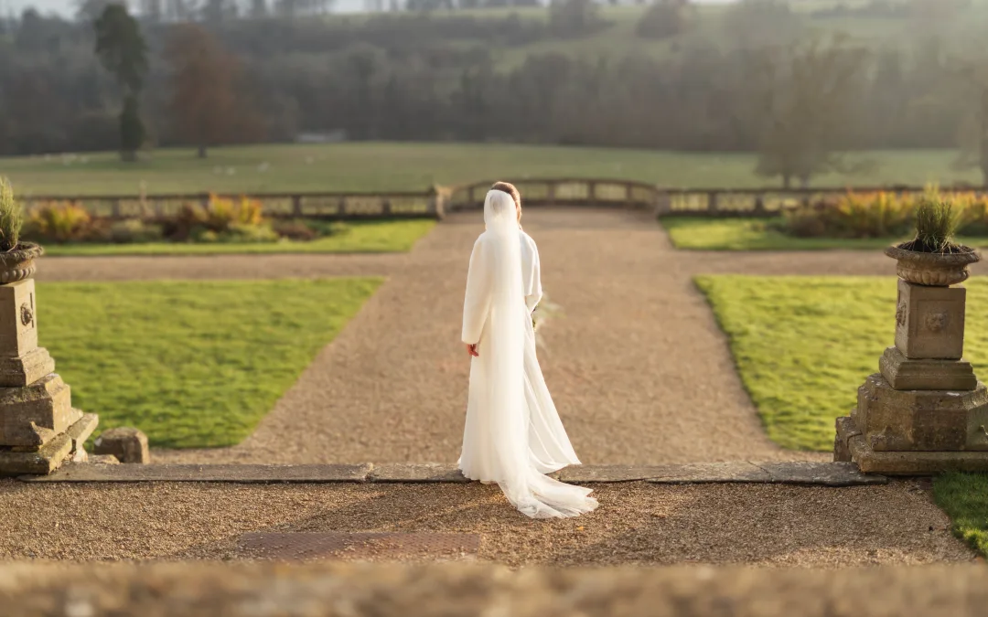 Orchardleigh Wedding Photographer captures a bride gracefully walking down a path in the beautiful garden.