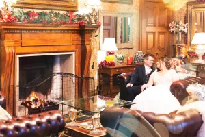 A bride and groom sitting in front of a fireplace during their wedding, captured beautifully by the talented Orchardleigh Wedding Photographer.