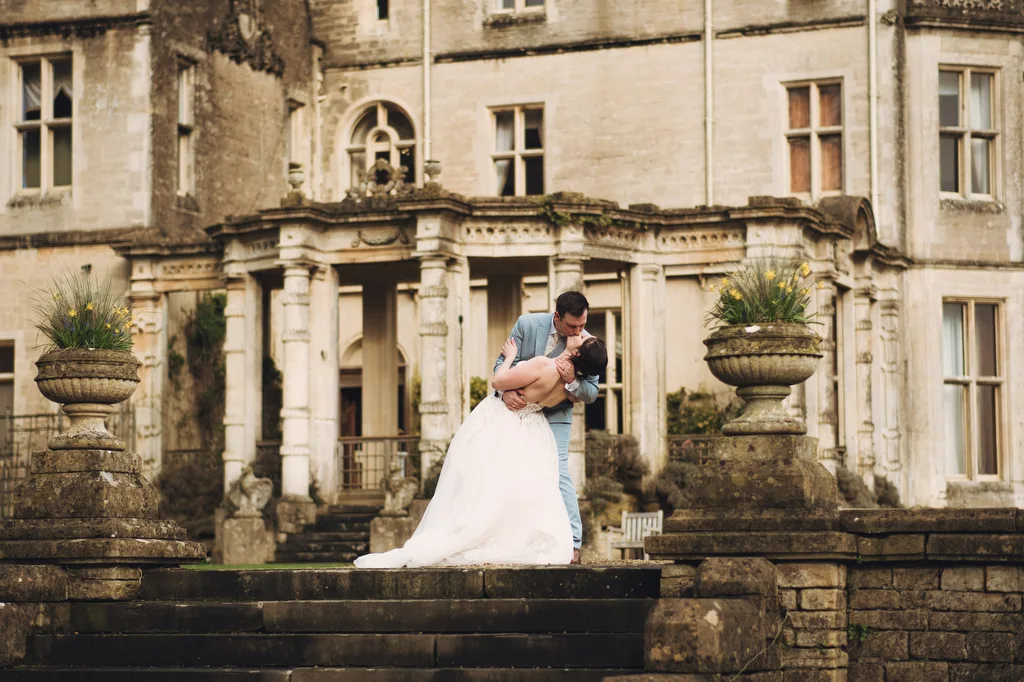 Bride and groom embracing in front of the historic Orchardleigh House.