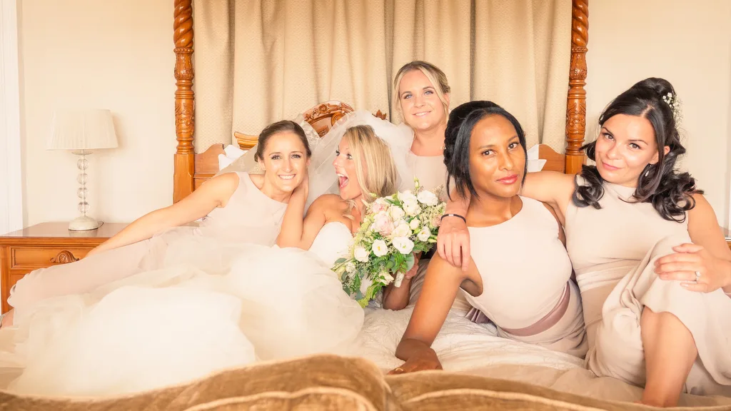 A group of bridesmaids posing on a bed captured by a world-class wedding photographer.
