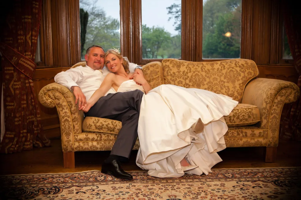 A bride and groom sitting on a couch in a large room, enjoying their wedding day in St. Andrie's Park with 20% off their wedding photography wedding photography