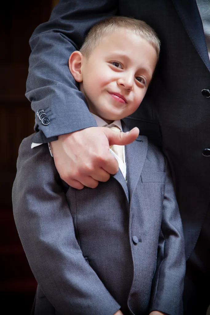 A man in a suit is holding a little boy at St. Andrie's Park wedding Photographer