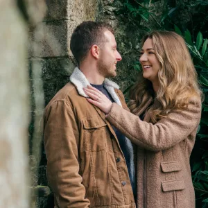 Stourhead Wedding Photographer10 An engaged couple standing in front of a stone wall, captured by a Stourhead Wedding Photographer.