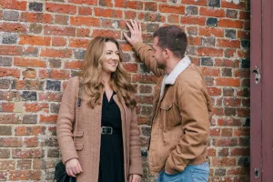 A couple leaning against a brick wall captured by a Stourhead Wedding Photographer.
