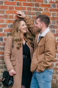 Stourhead Wedding Photographer23 Two people, an engaged couple, embracing against a brick wall.