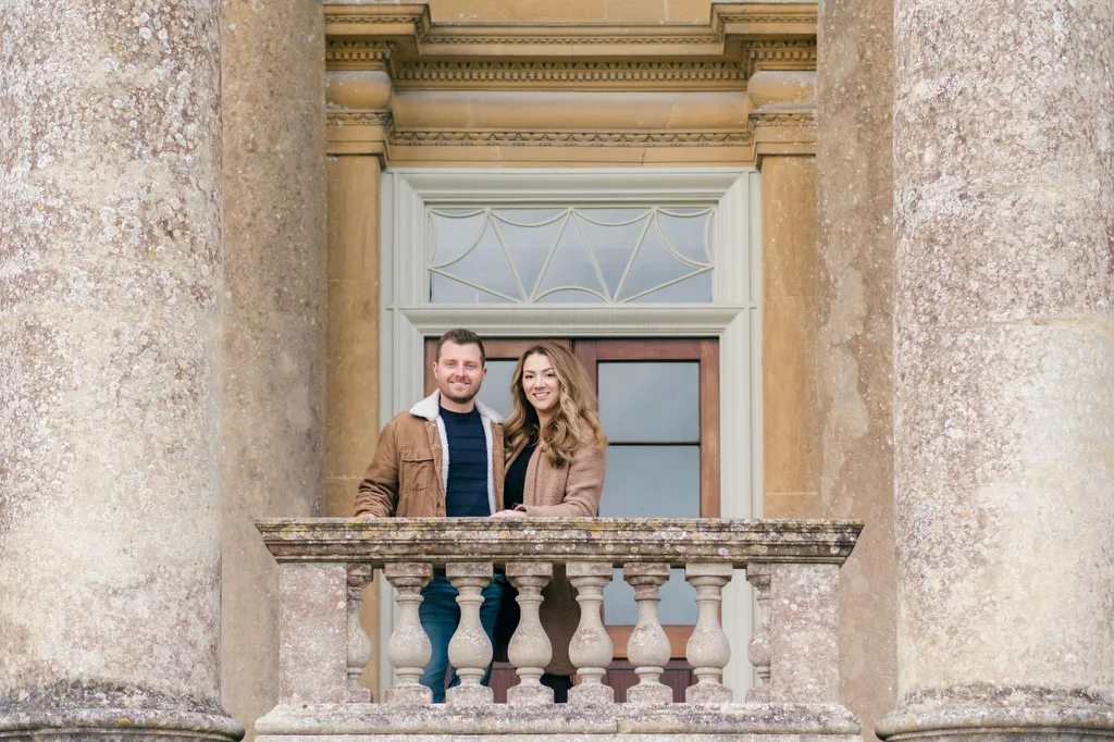 A Stourhead Wedding Photographer captures a couple standing on the balcony of an old building.