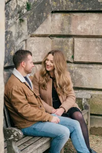 Stourhead Wedding Photographer35 A couple sits on a bench in front of a stone wall, captured by a Stourhead Wedding Photographer.