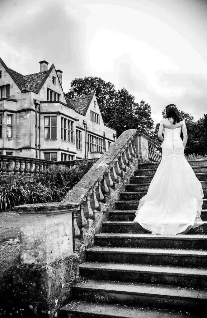 A bride is walking down the stairs of a mansion at Coombe Lodge for discount on wedding Photography