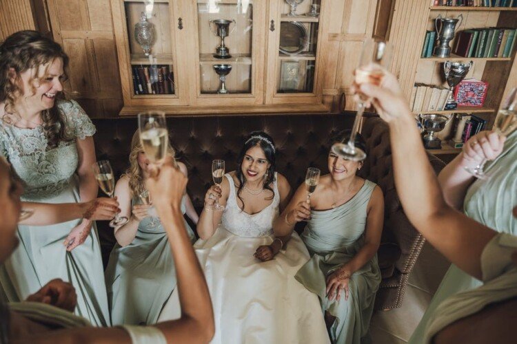 Beautiful Bride raising a glass of champagne with her friends at Farleigh Hose