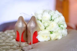 www.thefxworks.co.uk A pair of high heeled shoes in red, accompanied by a bouquet of white flowers at Orchardleigh House.