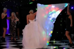 a woman in a white dress is walking on a black and white checkered floor.