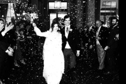 At Hartham Park Weddings, a bride and groom smile radiantly as they walk through a crowd showering them with confetti.