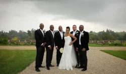 www.thefxworks.co.uk A bride in a white dress with five groomsmen in black suits posing for a photograph outdoors at Orchardleigh House Weddings.