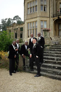 www.thefxworks.co.uk A group of men in formal attire smiling and posing for a photo on the steps outside the elegant Orchardleigh House.