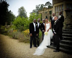 www.thefxworks.co.uk A wedding party posing for a photograph outside Orchardleigh House, featuring a bride in a white gown and groomsmen in formal black attire.