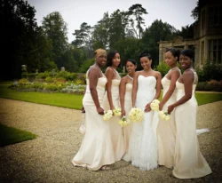www.thefxworks.co.uk A bride poses with her bridesmaids in a garden setting at Orchardleigh House, all dressed in formal attire for a wedding.