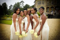 www.thefxworks.co.uk A bride with her bridesmaids, all dressed in elegant attire, holding bouquets and posing for a photo at Orchardleigh House Weddings.