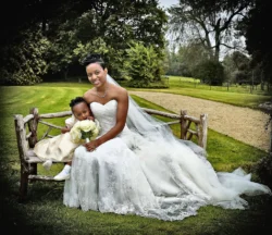 www.thefxworks.co.uk A bride and a young flower girl sitting on a wooden bench outdoors at Orchardleigh House.
