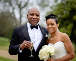 www.thefxworks.co.uk A bride in a white dress holding a bouquet stands with a man in a tuxedo holding a champagne flute, both smiling for a picture at an Orchardleigh House Wedding.