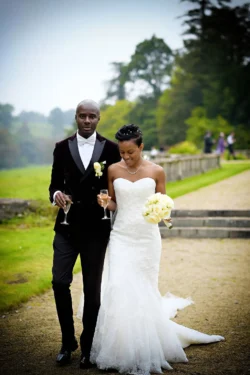 www.thefxworks.co.uk A couple in wedding attire walking together with glasses in hand at Orchardleigh House.
