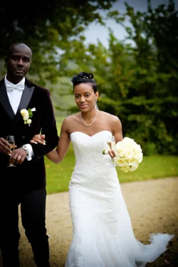 www.thefxworks.co.uk A bride and groom walking together at Orchardleigh House Weddings, the bride holding a bouquet and the groom with a glass in hand, both dressed in formal wedding attire.