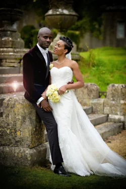 www.thefxworks.co.uk A newlywed couple posing for a photo outdoors at Orchardleigh House, with the bride in a white gown holding a bouquet, and the groom in a dark suit with a velvet jacket.