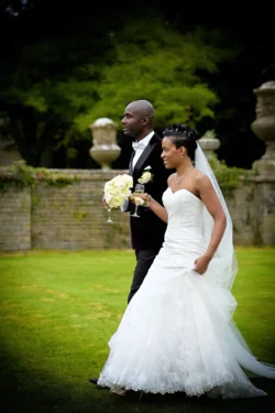 www.thefxworks.co.uk A couple dressed in wedding attire walking together through the Orchardleigh House garden setting.