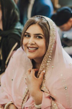 A woman wearing a pink traditional outfit with sequins smiles at the camera, perfectly captured, showcasing the quality of Fuji Cameras for weddings.