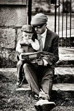 www.thefxworks.co.uk A man in a suit reading a book to his son during a wedding at Orchardleigh.