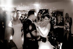 A bride and groom dance surrounded by friends and family at an Orchardleigh Weddings reception. Some guests are clapping and smiling, and there are bubbles in the air, creating a magical atmosphere.