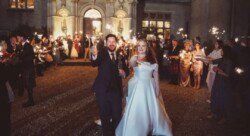 A bride and groom stand outdoors at night, surrounded by guests holding sparklers in celebration at their Orchardleigh Weddings venue.