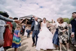 A bride and groom leave the Orchardleigh House ceremony with confetti thrown at them, captured by a talented wedding photographer.