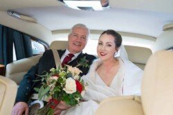 Evoto Bride and groom beaming in a car, reminiscent of classic Orchardleigh House photos. She cradles a bouquet in her white dress, while he looks dapper in his suit.
