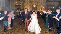 A newlywed couple walks through a group of people holding sparklers outside Orchardleigh House at night, capturing the magic in stunning photos.
