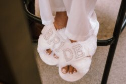 Person wearing white fuzzy slippers with the word "BRIDE" in rhinestones on the straps, perfect for a beautiful Croftview weddings ceremony at Hinton Park.