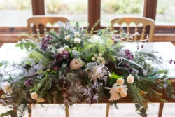 An arrangement of flowers on a wooden table captured by the Orchardleigh House Wedding Photographer.