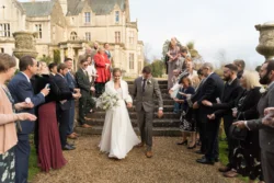 A bride and groom elegantly walking down the steps of a castle, captured by an Orchardleigh wedding photographer.