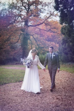 A bride and groom walking down a woodsy path captured by Orchardleigh Wedding Photographer.